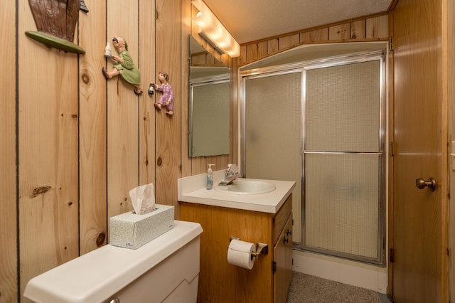 bathroom featuring wooden walls, a shower with shower door, vanity, toilet, and a textured ceiling