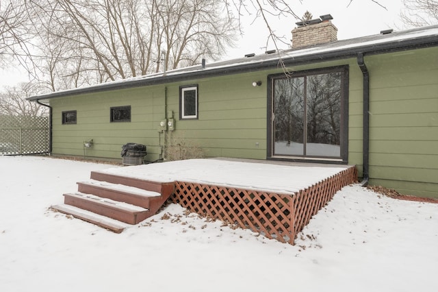 snow covered back of property with a deck