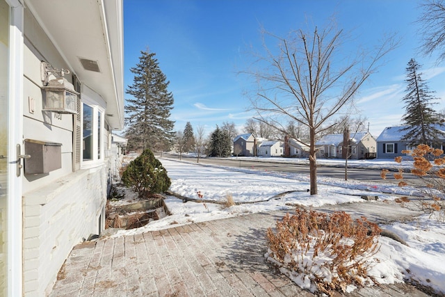 yard layered in snow featuring a residential view