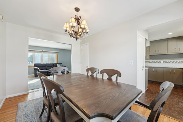 dining room featuring a chandelier, baseboards, and light wood finished floors