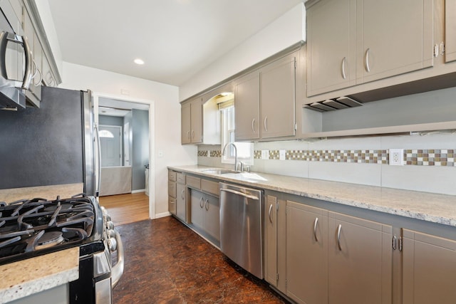 kitchen featuring decorative backsplash, appliances with stainless steel finishes, gray cabinets, and a sink