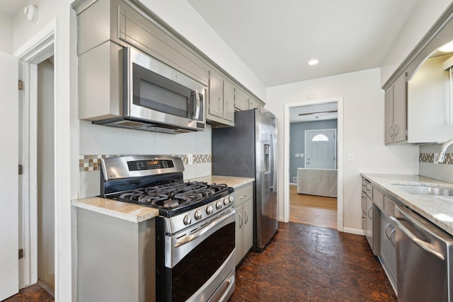 kitchen featuring stainless steel appliances, a sink, decorative backsplash, and gray cabinetry