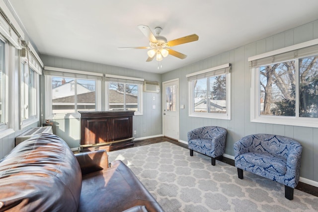 sunroom with a healthy amount of sunlight, a ceiling fan, and an AC wall unit