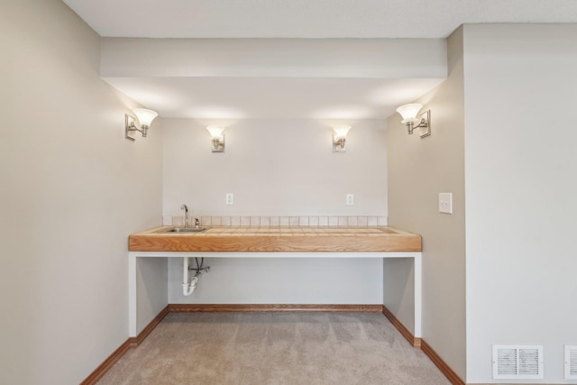 interior space with baseboards, visible vents, and a sink