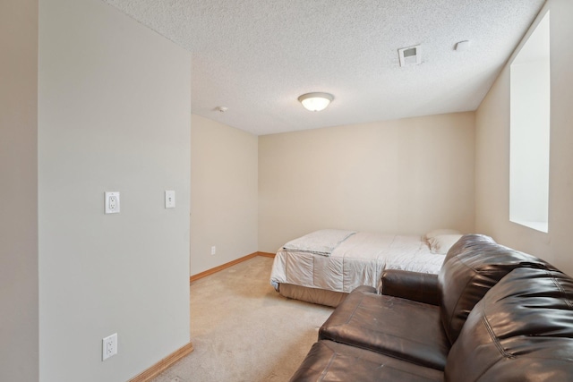 bedroom with light colored carpet, visible vents, baseboards, and a textured ceiling