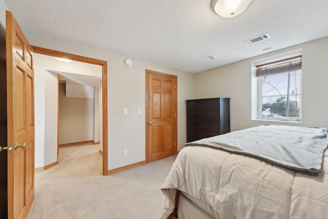 bedroom featuring light colored carpet, visible vents, a textured ceiling, and baseboards