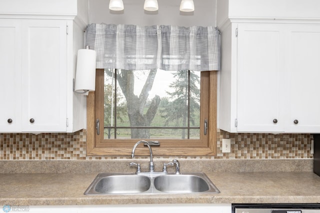 kitchen with a sink, light countertops, white cabinetry, backsplash, and dishwasher