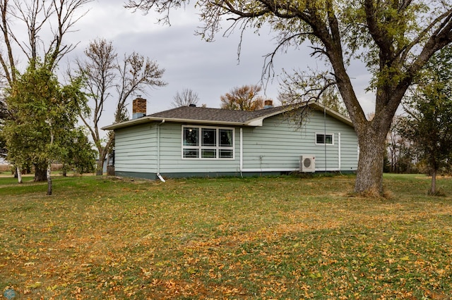 view of side of property featuring ac unit, a yard, and a chimney