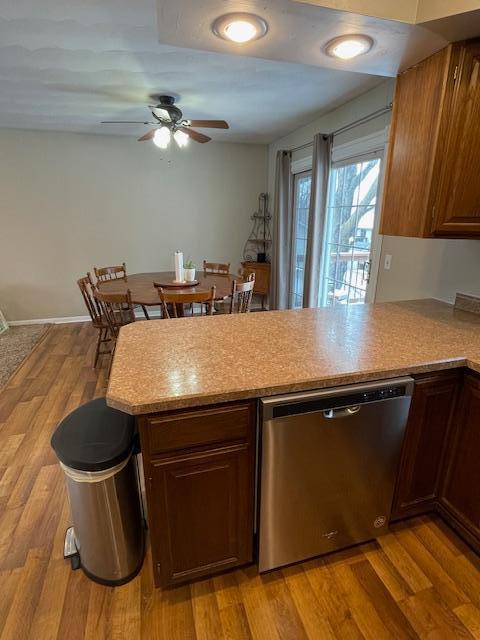 kitchen with ceiling fan, stainless steel dishwasher, light hardwood / wood-style floors, and kitchen peninsula