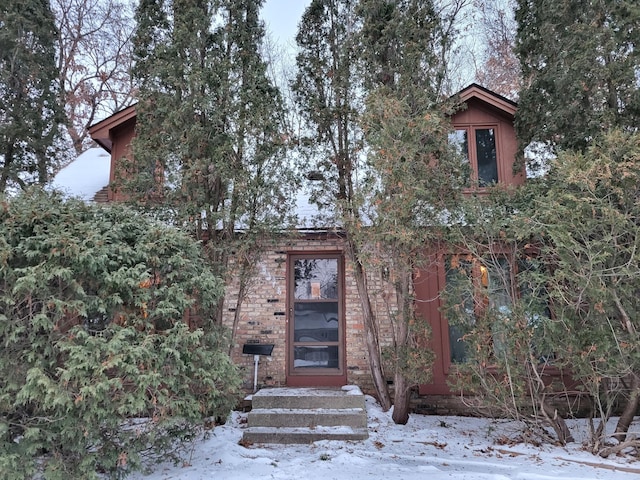 snow covered property entrance with brick siding