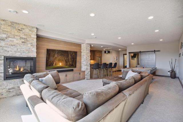 4765 Augusta St, Orono, MN 55364 - living area with light colored carpet, a textured ceiling, a barn door, recessed lighting, and a stone fireplace