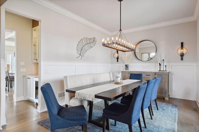 4765 Augusta St, Orono, MN 55364 - dining room featuring wood finished floors, crown molding, a wainscoted wall, a chandelier, and a decorative wall