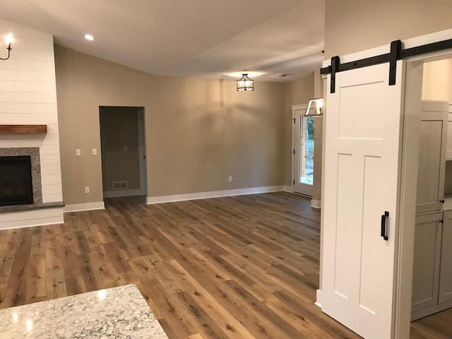 unfurnished living room featuring a barn door and dark wood-type flooring