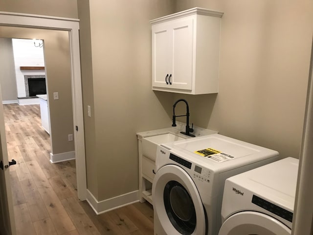 washroom with cabinets, independent washer and dryer, sink, and light wood-type flooring