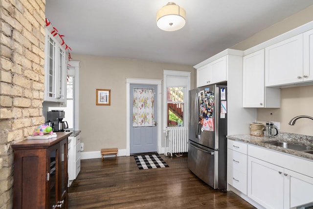 kitchen featuring white cabinets, radiator heating unit, glass insert cabinets, freestanding refrigerator, and a sink