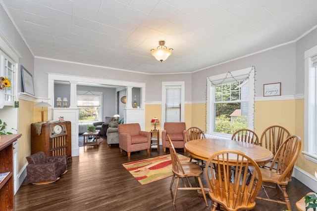 dining area featuring decorative columns, ornamental molding, and wood finished floors