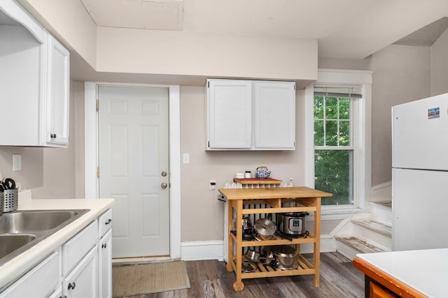 kitchen with baseboards, white cabinets, dark wood-style flooring, freestanding refrigerator, and light countertops