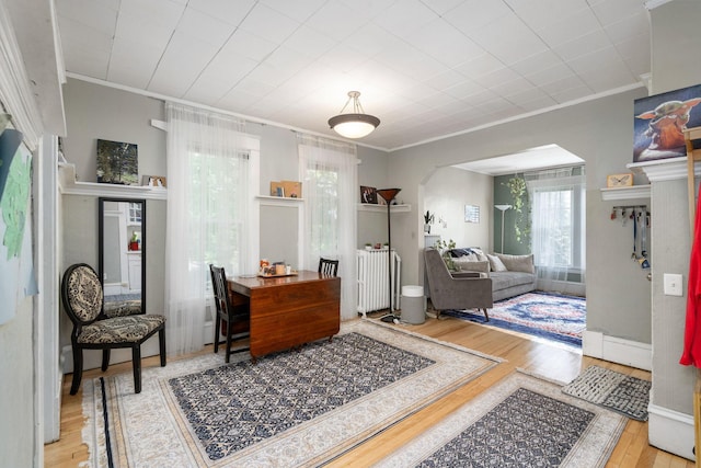 interior space with light wood-type flooring, arched walkways, ornamental molding, and baseboards