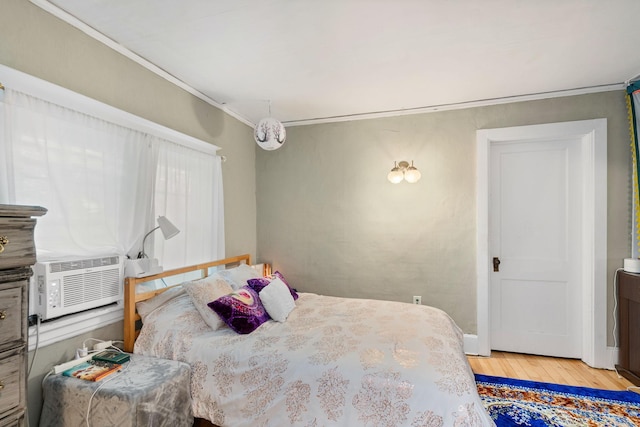 bedroom with ornamental molding, cooling unit, and wood finished floors