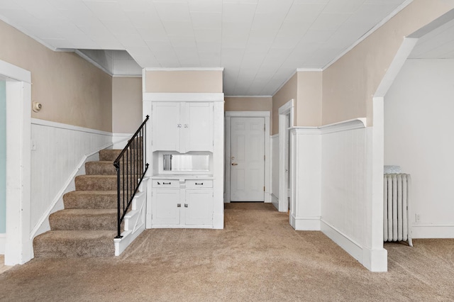 interior space featuring carpet floors, ornamental molding, wainscoting, and radiator