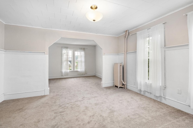 interior space with arched walkways, carpet floors, and radiator heating unit