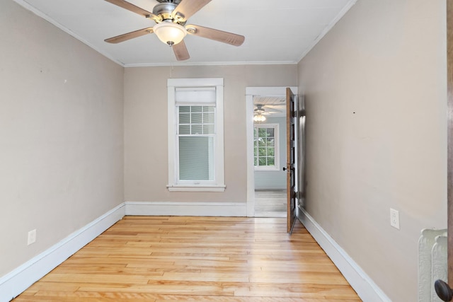 spare room featuring light wood finished floors, baseboards, and crown molding