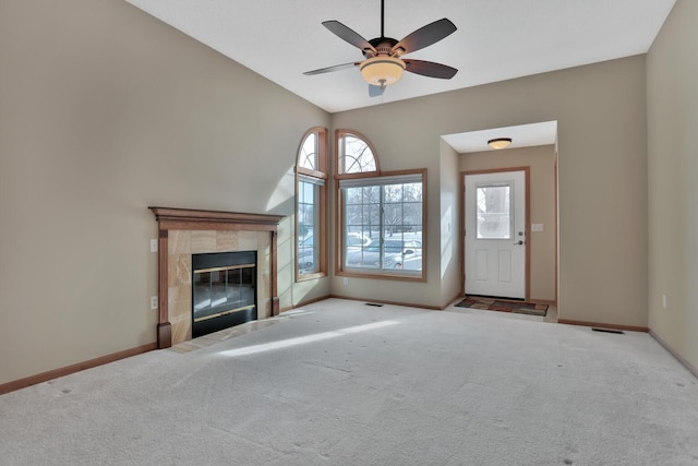 unfurnished living room featuring a tile fireplace, light carpet, and ceiling fan