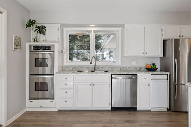 kitchen featuring appliances with stainless steel finishes, sink, white cabinets, and light wood-type flooring