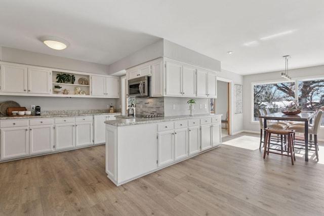 kitchen with decorative light fixtures, light stone countertops, light hardwood / wood-style floors, and white cabinets