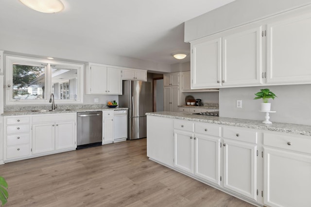 kitchen with appliances with stainless steel finishes, sink, light hardwood / wood-style flooring, and white cabinets