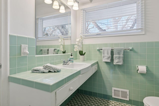 bathroom featuring tile walls, sink, and toilet