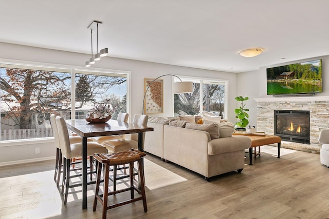 living room featuring a stone fireplace and light wood-type flooring