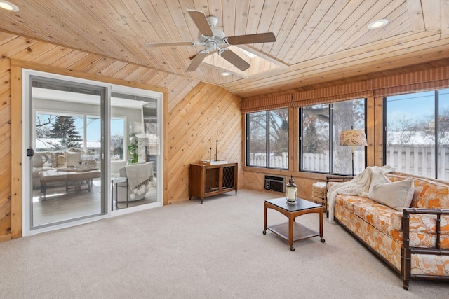 carpeted living room with ceiling fan, wood ceiling, a healthy amount of sunlight, and wood walls