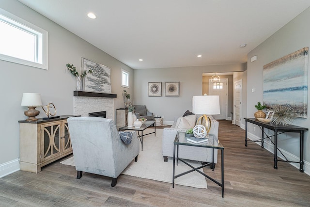 living room featuring hardwood / wood-style flooring, a stone fireplace, and a wealth of natural light