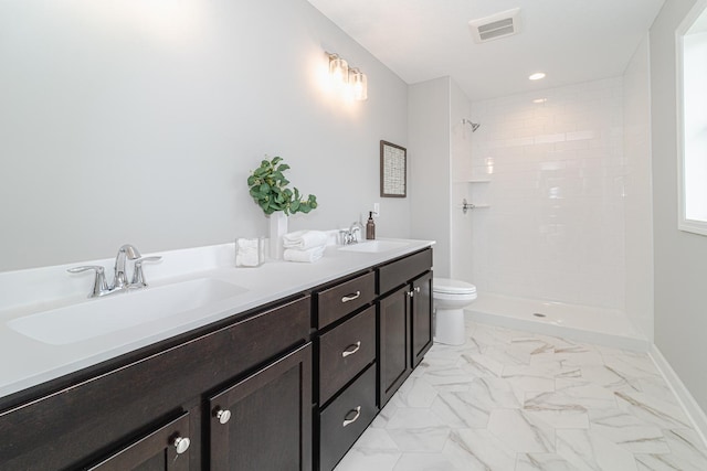 bathroom with vanity, toilet, and a tile shower