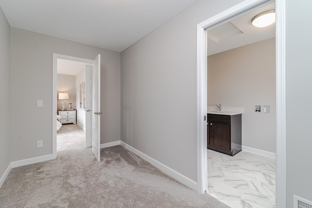 hall with light colored carpet and sink