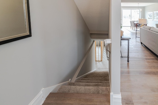 staircase featuring an inviting chandelier and hardwood / wood-style floors