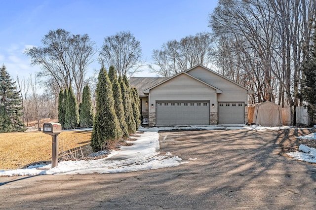 view of front of property with aphalt driveway, stone siding, a storage unit, and a garage