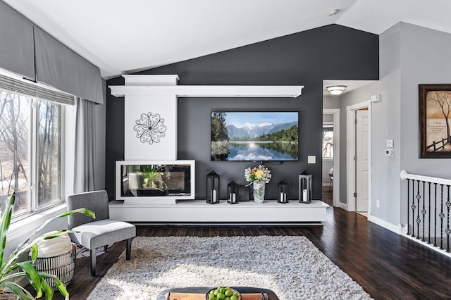 living area with lofted ceiling, wood finished floors, and baseboards