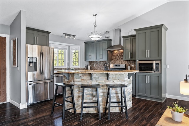 kitchen with stainless steel appliances, dark wood-type flooring, wall chimney exhaust hood, and decorative backsplash