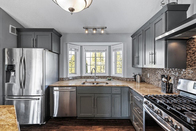 kitchen featuring visible vents, gray cabinets, a sink, stainless steel appliances, and exhaust hood