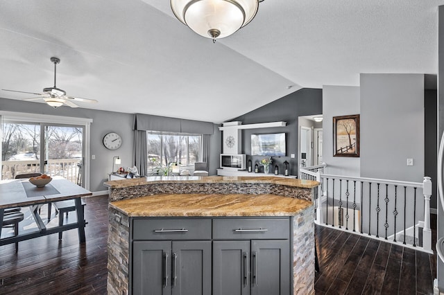 kitchen featuring vaulted ceiling, open floor plan, dark wood-style flooring, and gray cabinetry