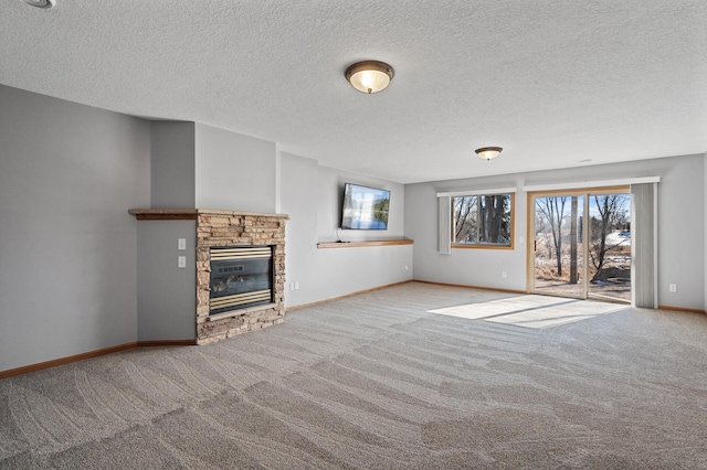 unfurnished living room with carpet flooring, a fireplace, a textured ceiling, and baseboards