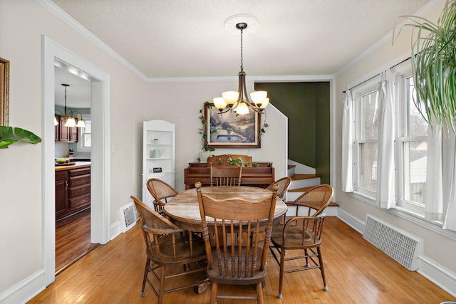 dining area with light wood-style floors, visible vents, a notable chandelier, and crown molding