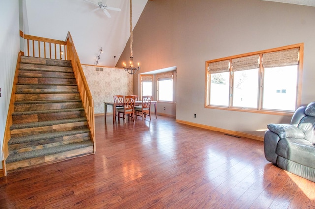 living room with a notable chandelier, hardwood / wood-style flooring, and high vaulted ceiling