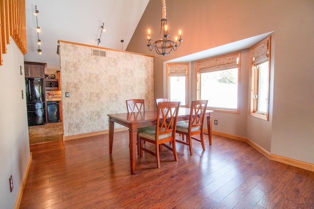 dining area with an inviting chandelier, dark wood-type flooring, and high vaulted ceiling