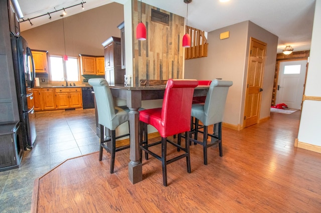 kitchen featuring sink, black appliances, hardwood / wood-style floors, and a kitchen bar