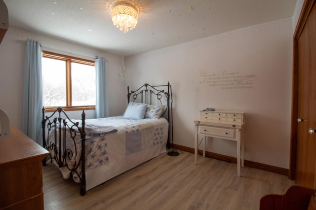 bedroom with a chandelier and light hardwood / wood-style floors