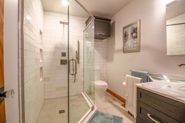 bathroom with a shower with door, vanity, tile patterned floors, and toilet