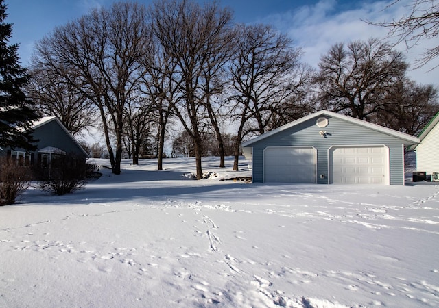 yard layered in snow featuring an outbuilding and a garage